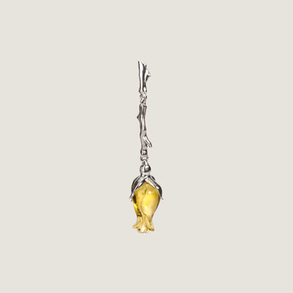 A single silver-colored earrings featuring a floral design with a yellow amber in the center, presented against a white background.