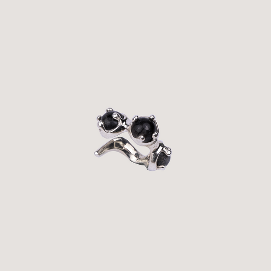 Silver earring with black gemstones on a light gray background