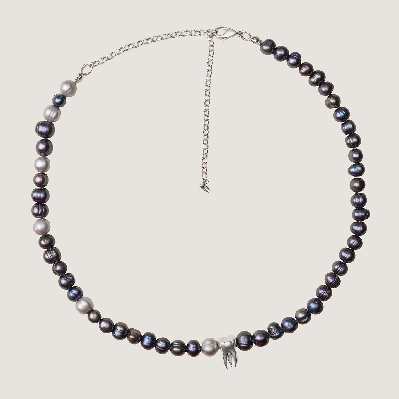 Pearl necklace with silver chain on a light gray background