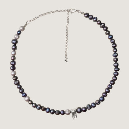 Pearl necklace with silver chain on a light gray background