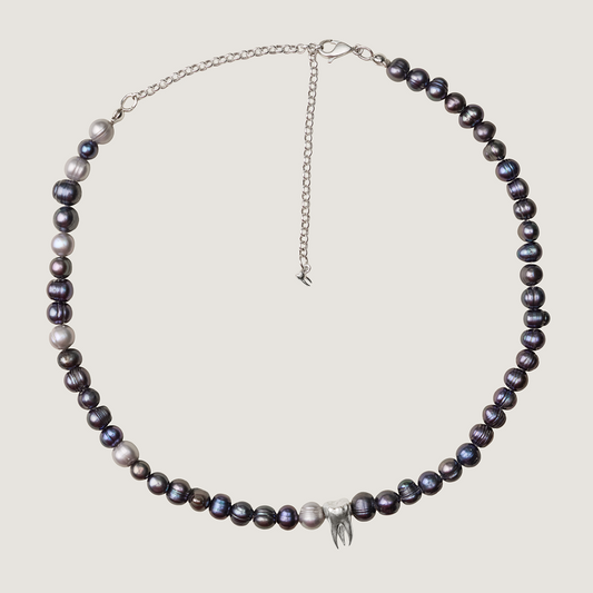 Pearl necklace with silver chain on a light gray background