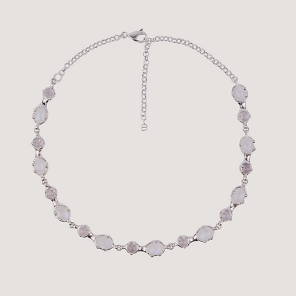 Silver necklace with gemstones on a light gray background