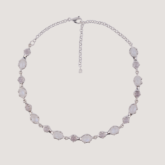 Silver necklace with gemstones on a light gray background